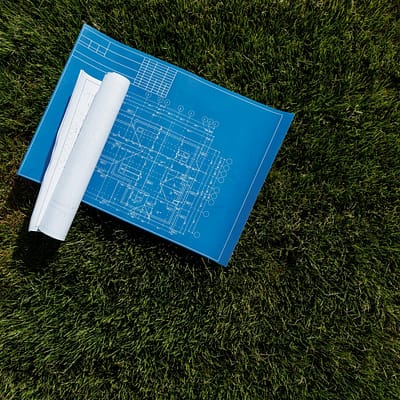 Top view of architectural blueprints on a grassy field, ideal for construction themes.